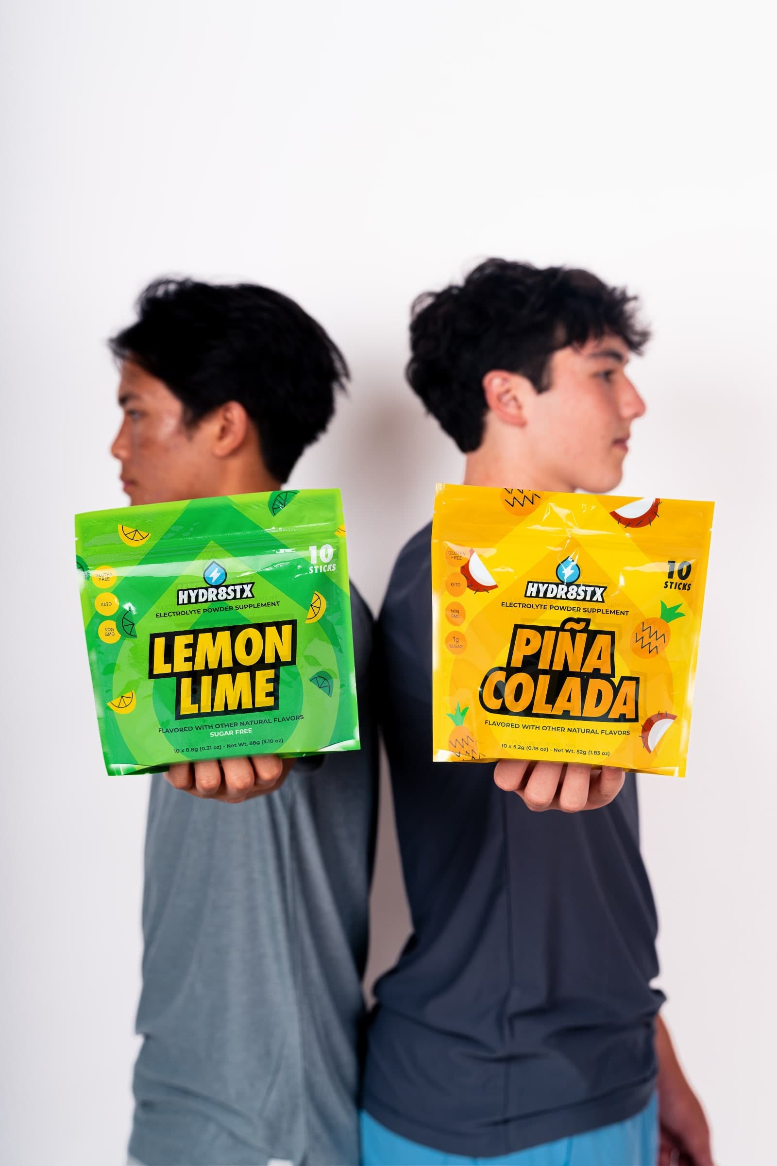 Hydr8Stx founders Dominic and Mason holding Lemon Lime and Piña Colada pouches